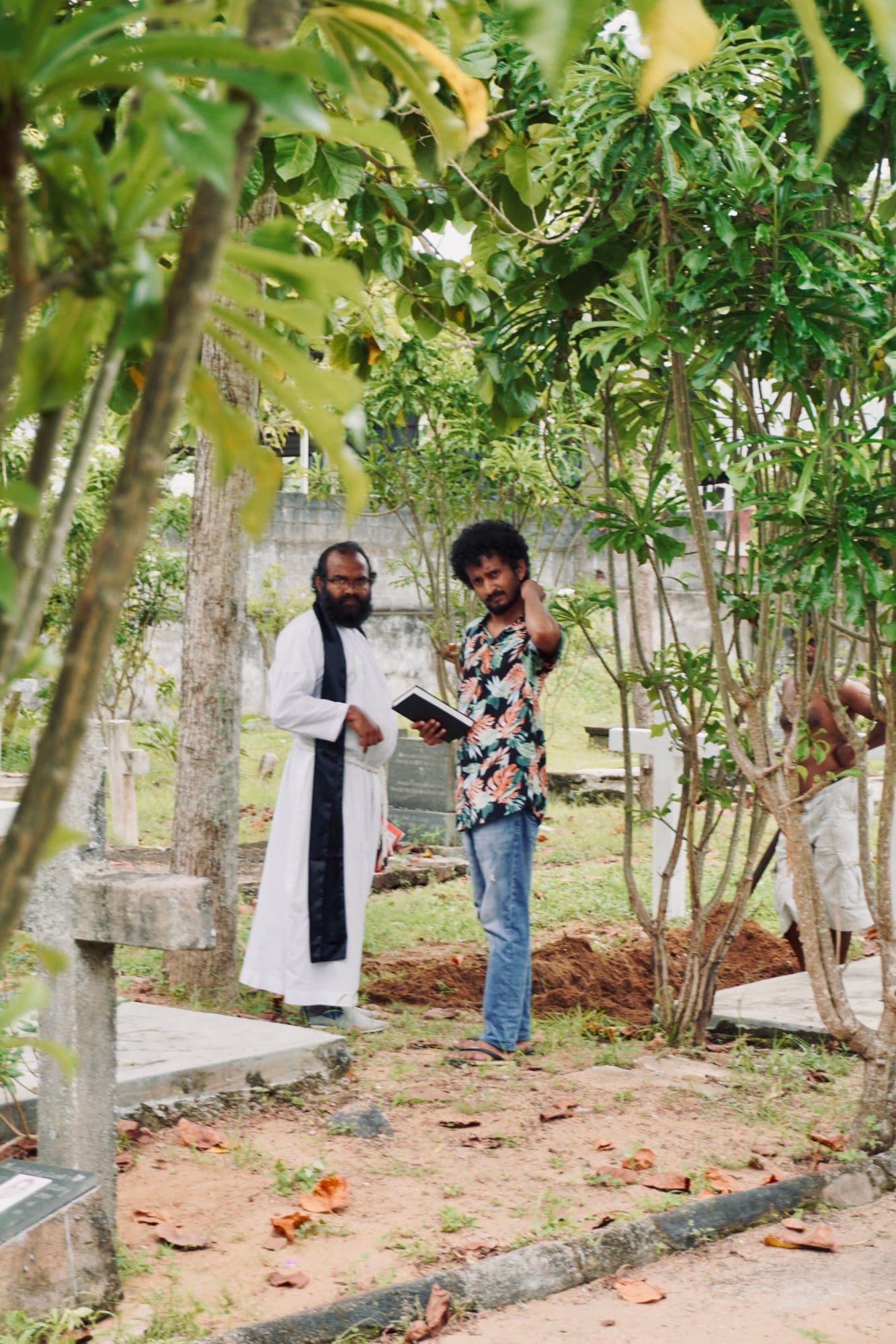The priest and lead actor rehearsing beside an open grave.